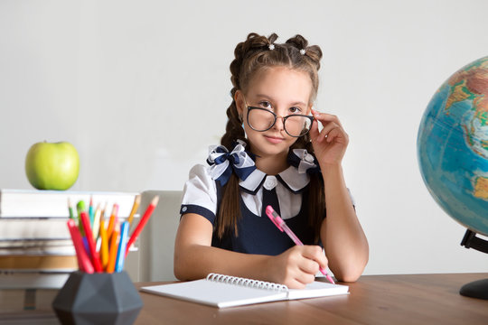 Portrait of school girl looking at camera while drawing is learning in class.
