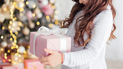 A little girl is holding a gift box