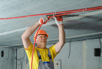 The electrician is fixing an electric corrugated tube.