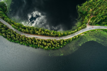 Road on a narrow piece of land between two lakes with forest