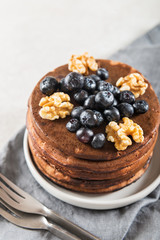 Stack of homemade chocolate pancakes with blueberries and chocol