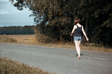 young girl walking barefoot on the road, the concept of summer and travel