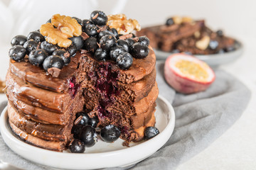 Stack of homemade chocolate pancakes with blueberries and chocol