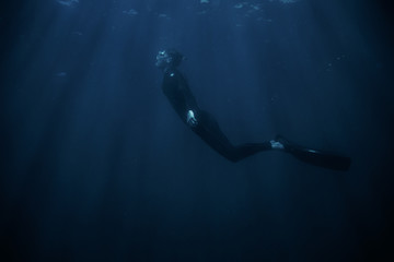 Man wearing in wetsuit snorkeling underwater.