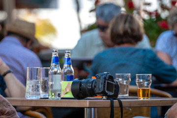 In the cafe on the table placed a camera, bottles and glasses.