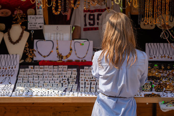 A woman in the souvenir kiosk choose amber jewelry.