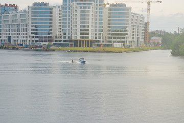 Construction of new houses on the river Bank. Boat with water skier. St. Petersburg, Russia.