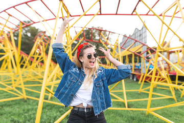 Happy girl rejoices on the background of a bright amusement park, smiles and looks away. Portrait...