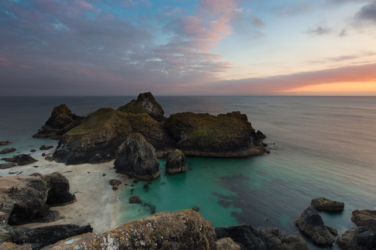 The beach and cliffs of Kynance Cove in Cornwall, UK which is a popular tourist destination at sunset in a picturesque landscape image