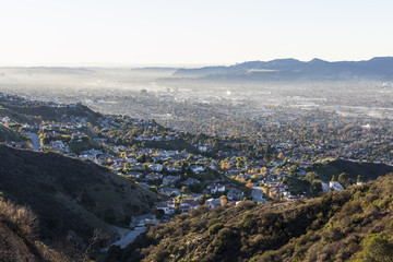 Smoggy hilltop view of canyon homes and downtown Burbank with the San Fernando Valley, the Santa Monica Mountains and Los Angeles California in background.