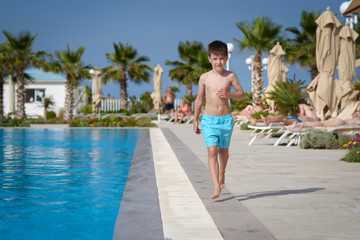 Portrait of smiling Caucasian boy in spending time in pool swimming at resort.