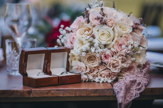 Close-up of bouquet with wedding rings on wooden table