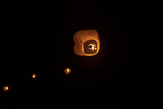 Low angle view of illuminated lanterns flying against sky at night