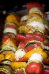Vegan skewers of various vegetables on the grill plate .