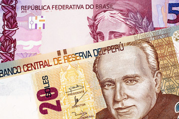 A macro image of a twenty Peruvian soles bank note with a purple Brazilian five reais bill 