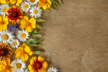 Blooming wildflowers and on a wooden background. Flower texture. Space for text.