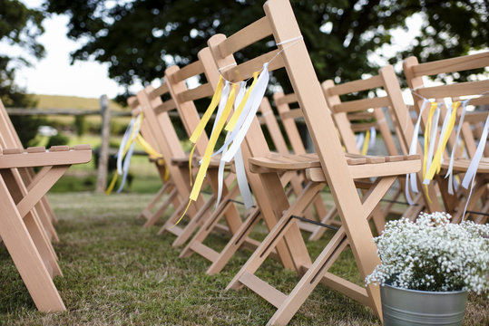 Wooden empty chairs arranged on grassy field at wedding reception