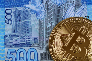 A close up image of a blue five hundred Kazakhstani tenge bill with a golden bitcoin