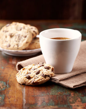 Cup of coffee and chocolate chip cookies. Symbolic image. Concept for a tasty snack. Sweet dessert. Rustic wooden background. Selective focus. Close up.  
