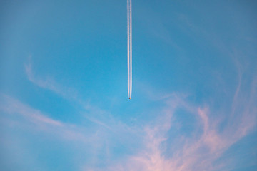 aircraft with contrail in morning sun