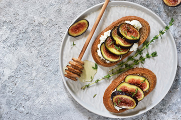 Toasts with ricotta, figs and honey for breakfast on a concrete background. Gourmet breakfast.