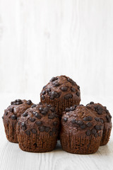 Chocolate muffins on white wooden background, side view. Close-up.