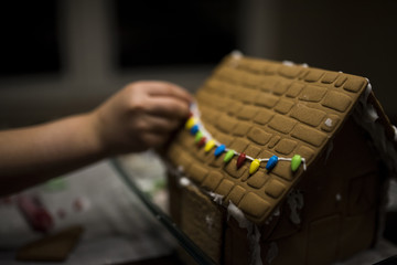 Cropped image of girl decorating gingerbread house on table at home during Christmas