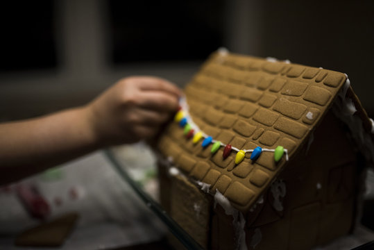 Cropped image of girl decorating gingerbread house on table at home during Christmas