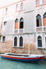Fototapeta na wymiar Old grey building and boat in venetian canal in Venice, Italy
