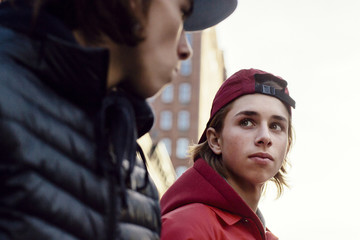 Low angle view of friends looking at each other while standing against clear sky in city