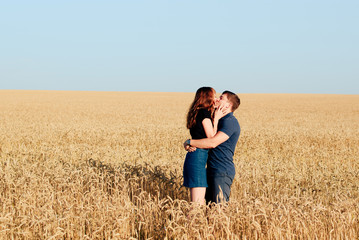 Naklejka na ściany i meble young loving couple in nature in summer on a background of field with oats