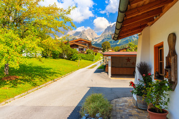 Road in Going am Wilden Kaiser mountain village on sunny summer day and beautiful traditional houses decorated with flowers, Tyrol, Austria