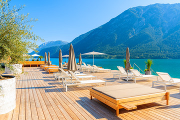 Chairs on pier in Pertisau town on sunny summer day on shore of Achensee lake, Tirol, Austria - obrazy, fototapety, plakaty