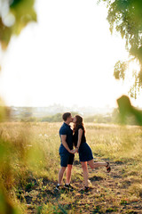 young loving couple in nature in summer on a background of green leaves