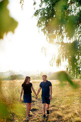 young loving couple in nature in summer on a background of green leaves