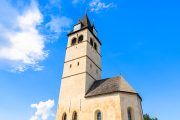 Fototapeta na wymiar Church tower in Kitzbuhel town against sunny blue sky, Tirol, Austria