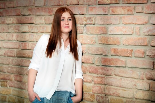 Ginger girl leaning against brick wall