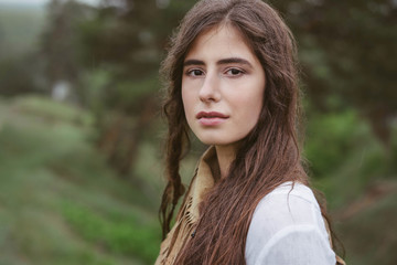Naklejka premium Portrait of brunette close-up, green background in nature, outdoor. Natural make-up and hairstyle.