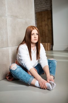 Young girl sitting on floor at home bored