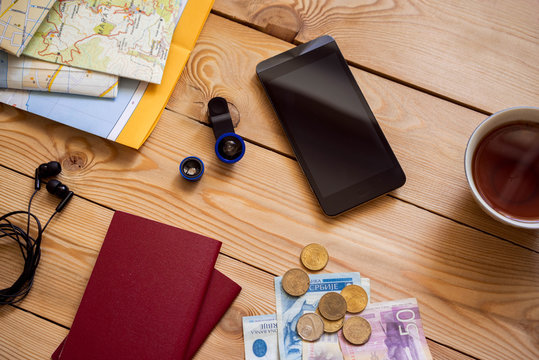 The concept of travel and the trip. Travel planning. Wooden table background on which are cards, camera, smartphone, money. 