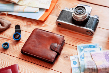 The concept of travel and the trip. Travel planning. Wooden table background on which are cards, camera, smartphone, money.