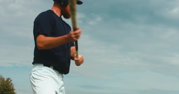 CU Portrait of batter baseball player hits a ball against cloudy sky. 4K UHD 60 FPS SLO MO RAW