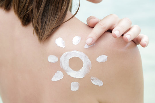 Woman with sun shaped sunscreen on her shoulder, skin protection concept