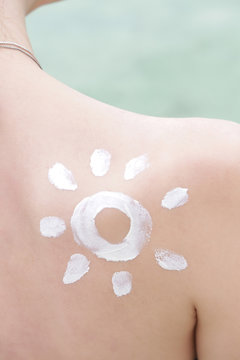 Woman with sun shaped sunscreen on her shoulder, skin protection concept