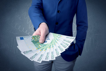 Young businessman holding large amount of bills with grungy background