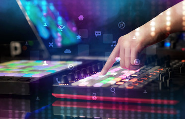 Hand mixing music on dj controller with social media concept icons
