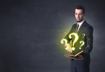 Businessman holding a book with question mark symbol.