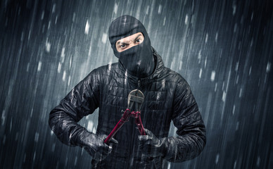 Naklejka premium Burglar in action in black clothes with rainy concept. 