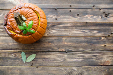 Baked stuffed pumpkin with spices, anise, pepper, cloves and cinnamon. Top view, brown rustic table. Copy space.