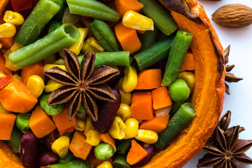 Stuffed pumpkin with carrots, beans, anise star decoration and sweet corn. Autumn mood, close-up, top view.